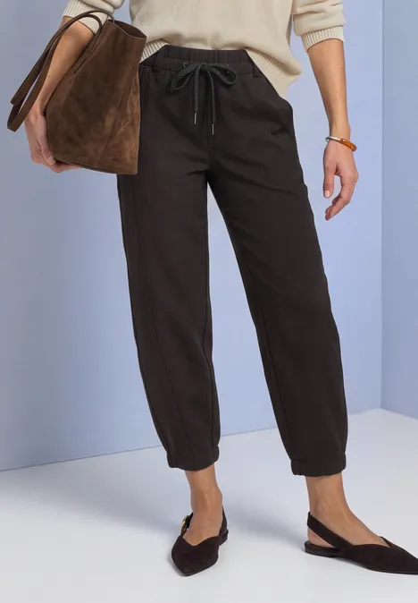 Pantalon de jogging noir à cordon et bas élastiqués, associé à des ballerines slingback plates et un sac.