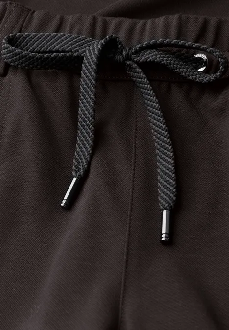Gros plan du cordon noir sur la ceinture en tissu texturé foncé.