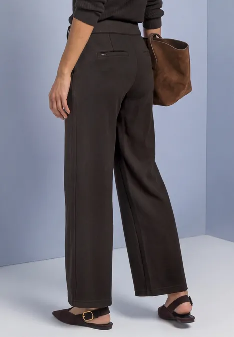High Waist Wide Leg Hose im Casual Fit black coffee Eine Person trägt dunkelbraune, weit geschnittene Hose, schwarze Sandalen und eine große braune Veloursleder-Tasche.