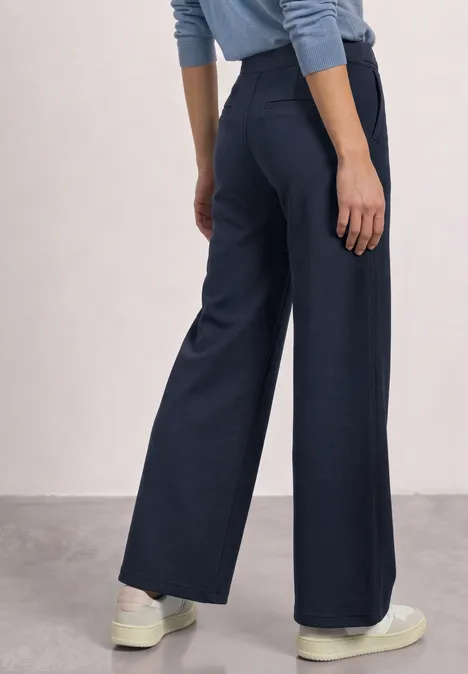 High Waist Wide Leg Hose im Casual Fit darkest blue Dunkelblaue, weite Hose mit hohem Bund, kombiniert mit weißen Sneakern. Rückenansicht.