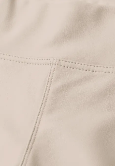 Close-up van een beige leren of kunstleren oppervlak met zichtbare naden