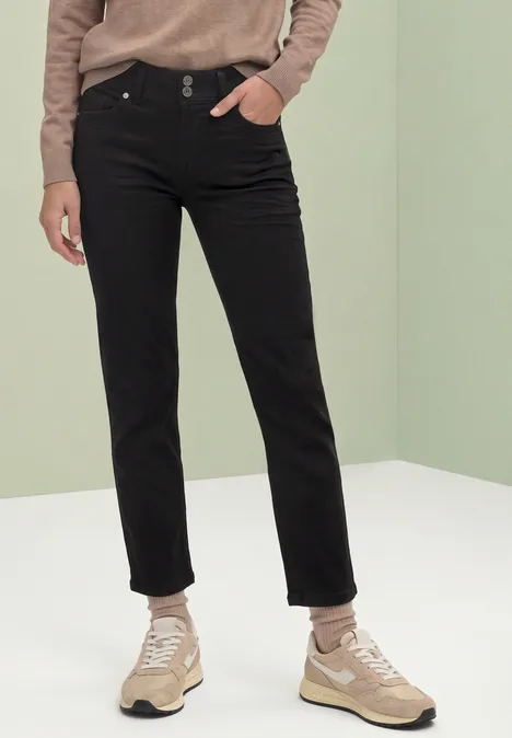 Mid Waist Straight Leg Jeans im Slim Fit soft black wash Person in schwarzen Jeans und beigen Sneakern vor hellem, minimalistischem Hintergrund.
