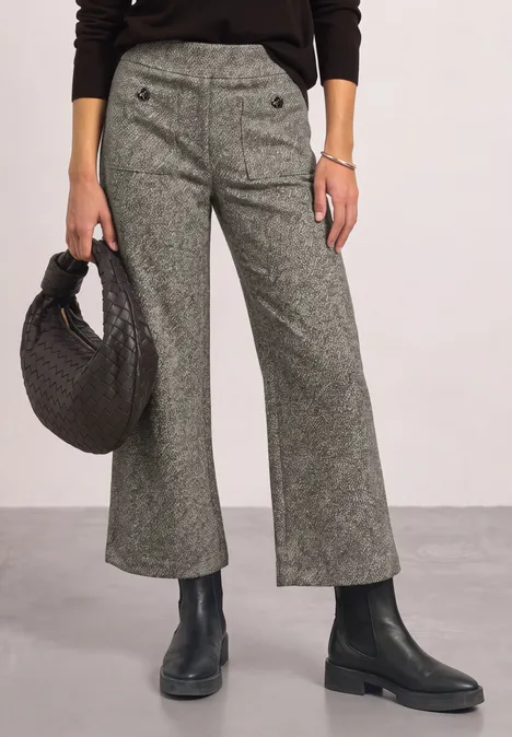 Graue, weit ausgestellte Hose mit Knopfdetail, schwarzer Handtasche und schwarzen Stiefeln.