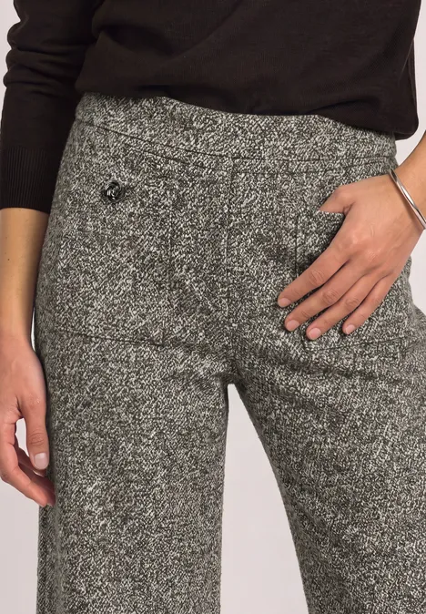Graue Tweed-Hose mit hoher Taille und dezentem Muster, Hand auf der Hüfte.
