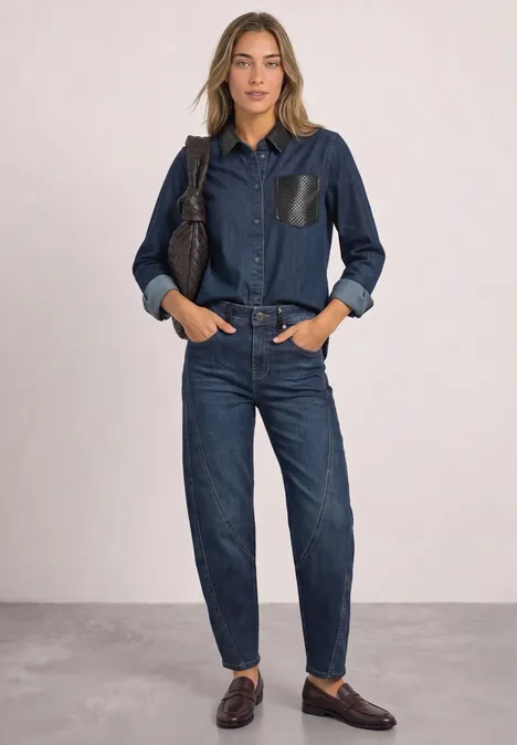 Dżinsy z luźnymi nogawkami typu „Loose Fit Barrel Leg” Dark blue authentic washed Kobieta ma na sobie ciemnoniebieską jeansową koszulę z elementami skórzanymi i dopasowane dżinsy, brązowe mokasyny.