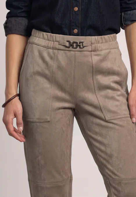 Jemand trägt eine hoch taillierte, beige Hose mit auffälligem Gürtel und Seitentaschen.