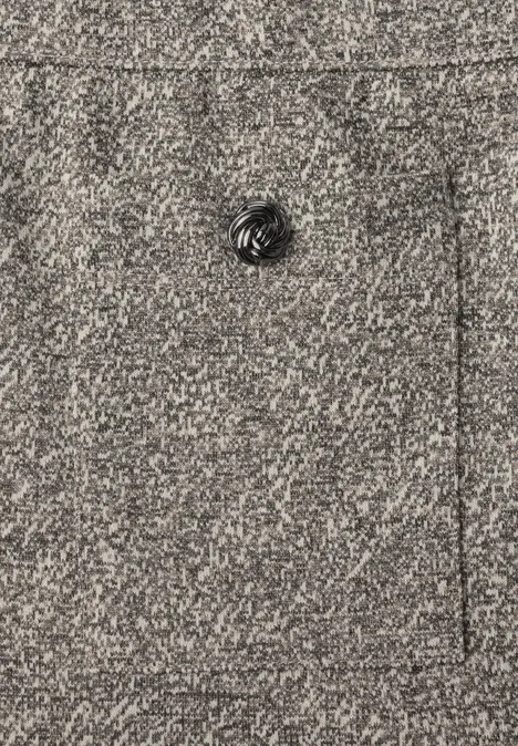 Nahaufnahme eines grauen Wollstoffs mit einem schwarzen, geriffelten Knopf.