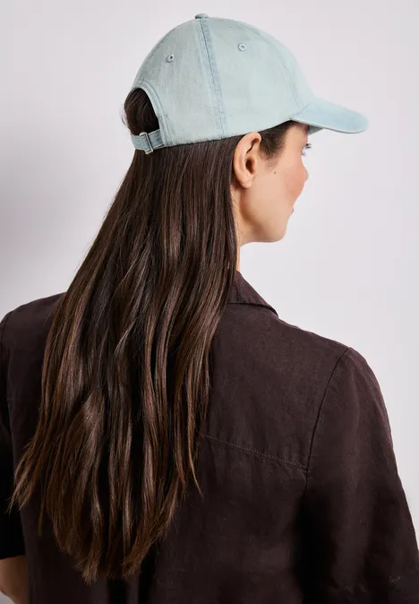 Personne de dos aux longs cheveux bruns portant une casquette de baseball bleu clair.