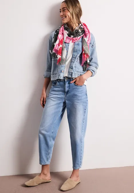 Frau in Jeansjacke, Bluse, Jeanshosen und buntem Schal