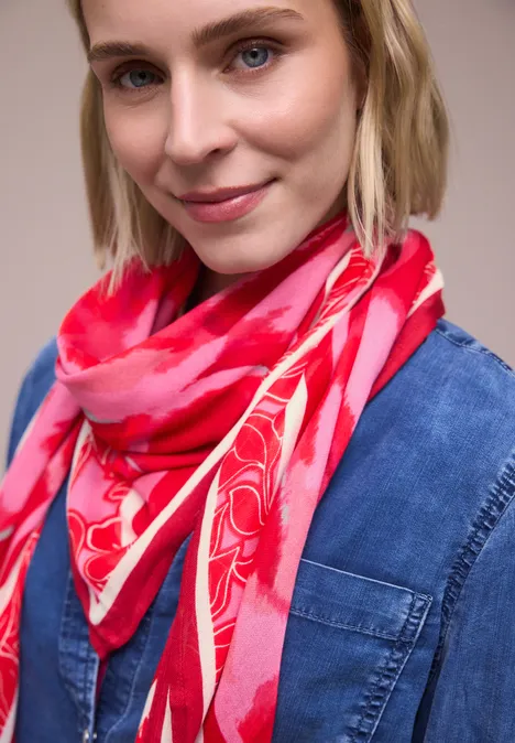 Person in Jeanshemd trägt ein pinkes Halstuch mit Blumenmuster.