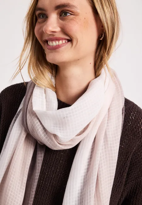 Person trägt hellen Schal locker um den Hals und einen dunkel gestrickten Pullover.