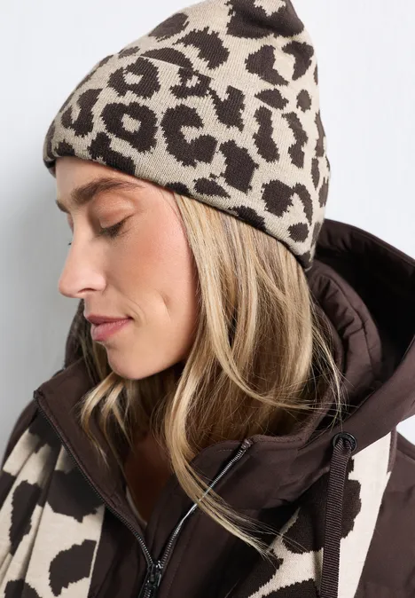 Frau im Profil trägt beige-braune Leopardenmuster-Mütze und passende Jacke