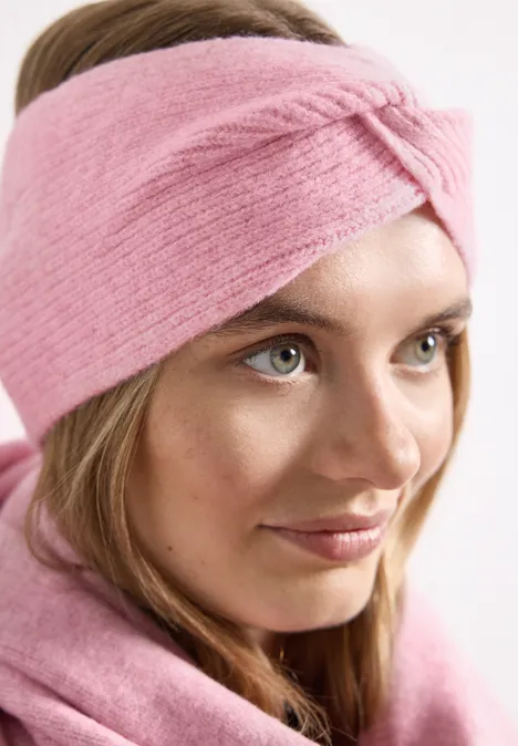 Feinstrick Stirnband in Unifarbe vintage blush mel. Junge Frau mit rosafarbenem Stirnband trägt passenden Schal und blickt sanft zur Seite.