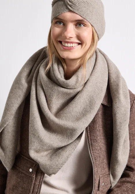 Fijn gebreide driehoekige sjaal in effen kleur Sandy Mocca Mel. Glimlachende vrouw met taupekleurige sjaal en hoofdband voor een witte achtergrond.