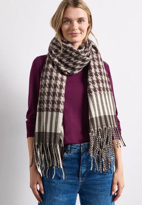Echarpe à motif pied-de-Poule Muddy Mocha Frau in Jeans und weinrotem Pullover trägt großen Hahnentritt-Schal mit Fransen.