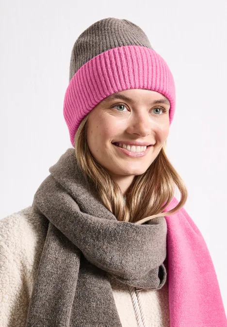 Feinstrick Beanie im Colorblock-Look warm blush Eine lächelnde Frau trägt eine zweifarbige Mütze (rosa und grau) und einen passenden Schal.