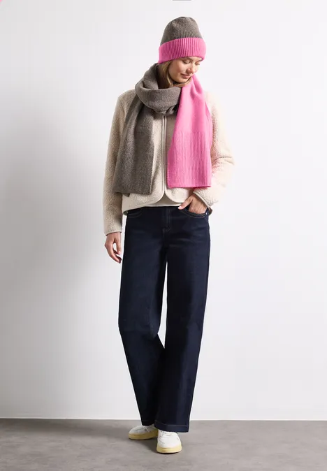 Feinstrick Beanie im Colorblock-Look warm blush Eine Frau trägt weite Jeans, helle Bluse, grauen und pinken Schal sowie passende Mütze vor weißem Hintergrund.