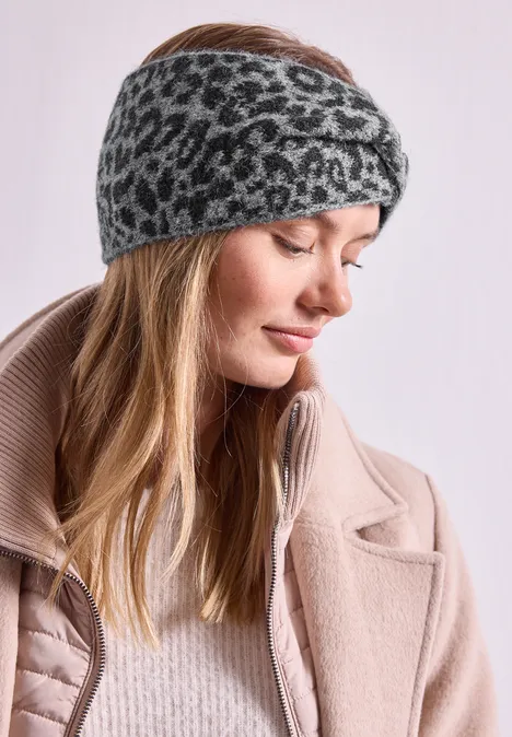 Jacquard Stirnband mit Leo-Muster Black Frau mit hellblondem Haar, trägt grauschwarzen Leoparden-Stirnband und beigen Mantel, schaut seitlich.