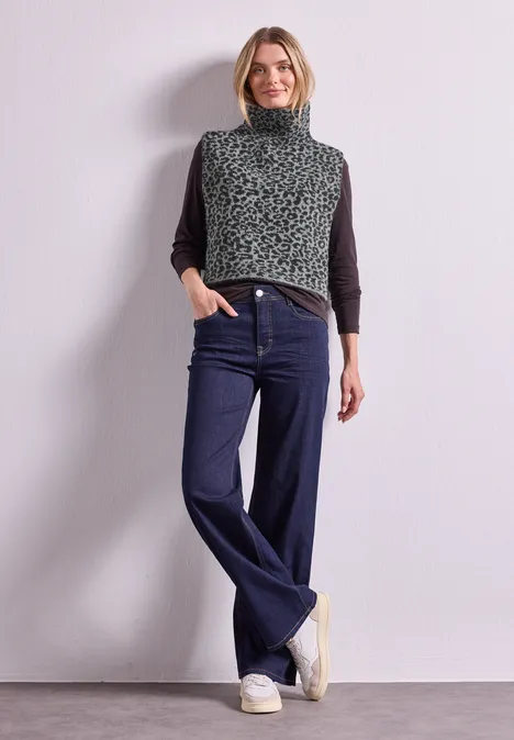 Jacquard Kragen mit Leo-Muster Black Frau in meliertem Rollkragen-Pullover, weiten Jeans und Sneakern vor neutralem Hintergrund.