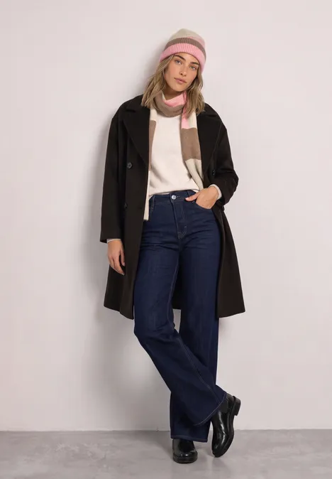 Schal mit Colorblock-Muster warm blush mel. Junge Frau mit schwarzem Mantel, Jeans, buntem Schal und Stirnband posiert vor hellem Hintergrund.