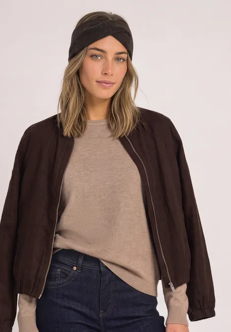 Stirnband in Melange-Optik Black Eine Frau trägt einen beigen Pullover, eine dunkelbraune Jacke, Jeans und ein schwarzes Stirnband.