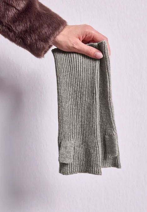 Armwärmer in Melange-Optik Muddy Mocha Eine Hand hält einen grauen, gerippten Strickschal vor hellgrauer Wand.