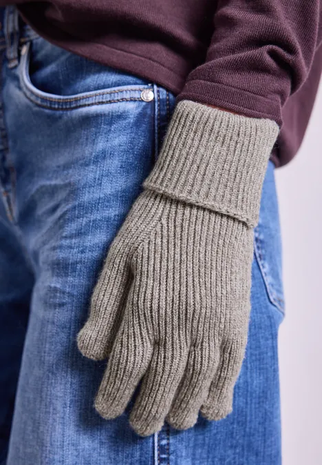 Handschuhe in Melange-Optik Muddy Mocha Grauer, gerippter Strickhandschuh an einer Hand vor blauer Jeans und dunkelrotem Pullover.