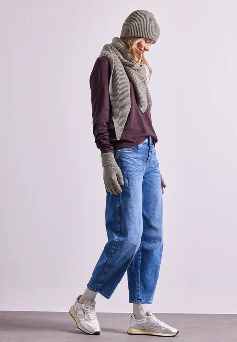Handschuhe in Melange-Optik Muddy Mocha Person in Winterkleidung mit Mütze, Schal, Fäustlingen, Pullover, Jeans und Sneakers.