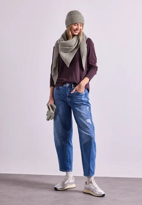 Dreiecksschal in Melange-Optik Muddy Mocha Frau in lässigem Outfit: graue Mütze, Schal, lila Pullover, zerrissene Jeans und Turnschuhe.