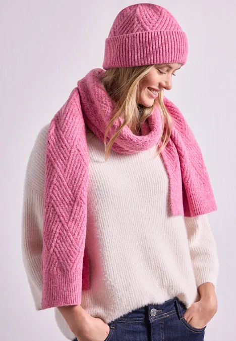 Femme portant un bonnet rose, une écharpe assortie et un pull clair