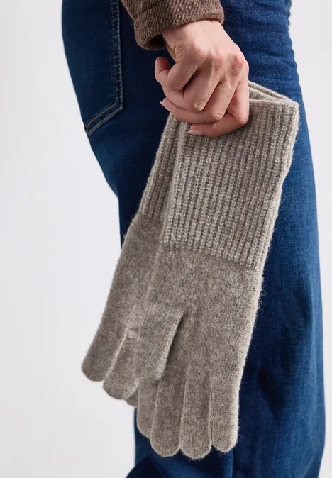 Feinstrick Handschuhe in Unifarbe Sandy Mocca Mel. Person hält graue, gestrickte Handschuhe mit Rippenbündchen, vor Jeans und Pullover.