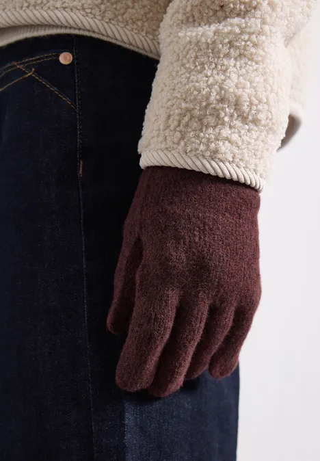 Feinstrick Handschuhe in Unifarbe rustic rouge mel. Eine Person trägt braune Strickhandschuhe und eine flauschige Fleecejacke.