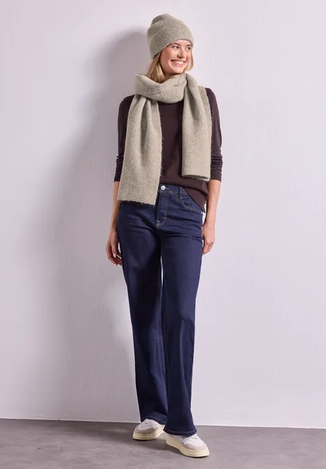 Schal im Melange-Look barley beige mel. Frau trägt Mütze, Schal, burgunderfarbenen Pullover, blaue Jeans und weiße Slip-on-Sneaker vor hellem Hintergrund.