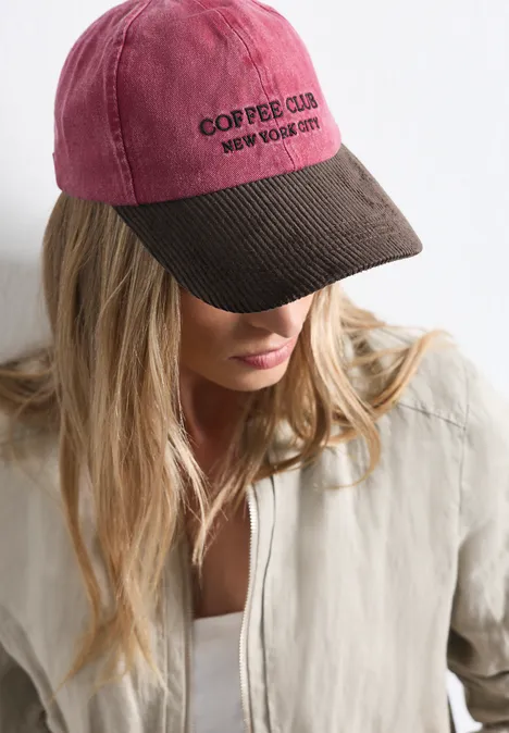 Frau mit blonden Haaren trägt zweifarbige Baseballcap mit Aufschrift "COFFEE CLUB"