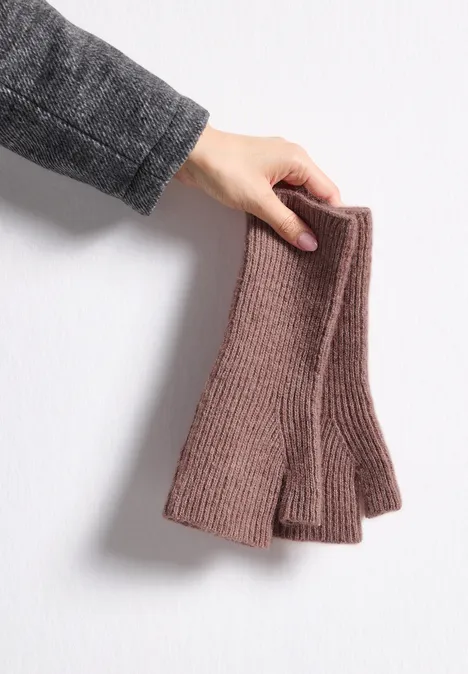 Armwärmer im Melange-Look vintage blush mel. Eine Hand hält ein Paar brauner, gestrickter fingerloser Handschuhe vor einer hellen Wand.