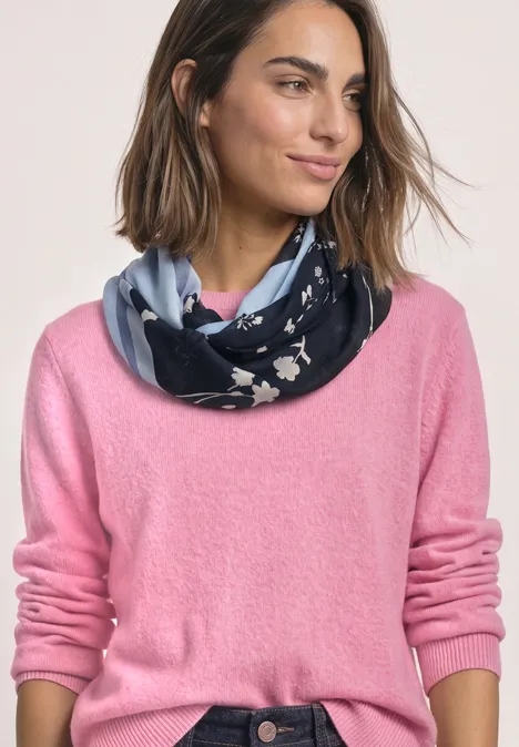 Vrouw met roze trui en marineblauwe sjaal met wit bloemenpatroon.