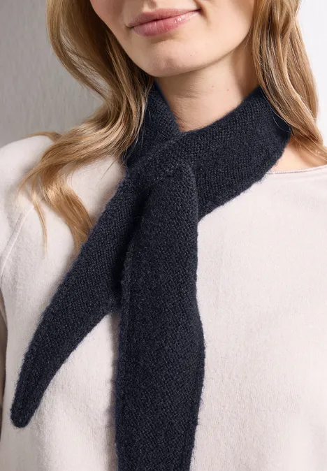 Mini-driehoekssjaal in effen kleur indigo night Vrouw met lichte trui draagt zachte zwarte sjaal, vooraan als een lus geknoopt.