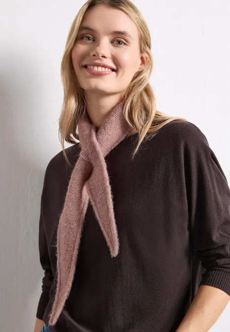 Eine junge Frau mit hellem Halstuch und braunem Pullover lächelt in die Kamera.