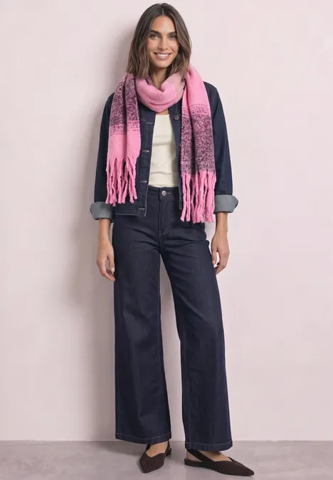 Frau in Jeansjacke, weißer Bluse, weiten Jeans, pinkem Schal und schwarzen Ballerinas vor hellem Hintergrund.
