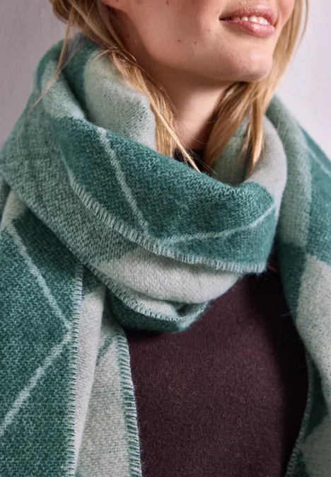 Langer Schal mit Fransen und Argyle-Muster stormy green Frau trägt weichen, karierter grüner Schal über einem dunklen Pullover, Nahaufnahme von Hals und Schultern.