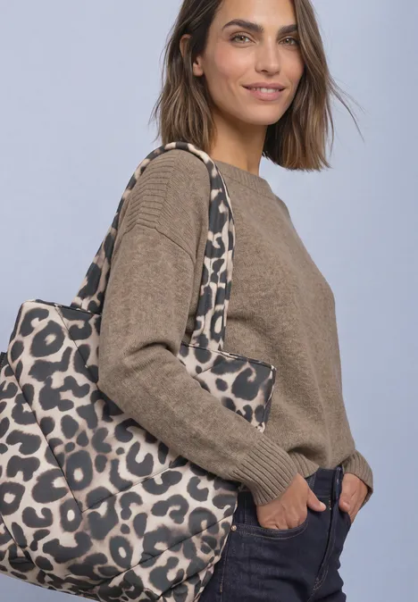 Sac cabas doublé à motif léopard multicolor Eine Frau trägt einen braunen Pullover, eine dunkelblaue Hose und eine große Leoparden-Print-Tasche.