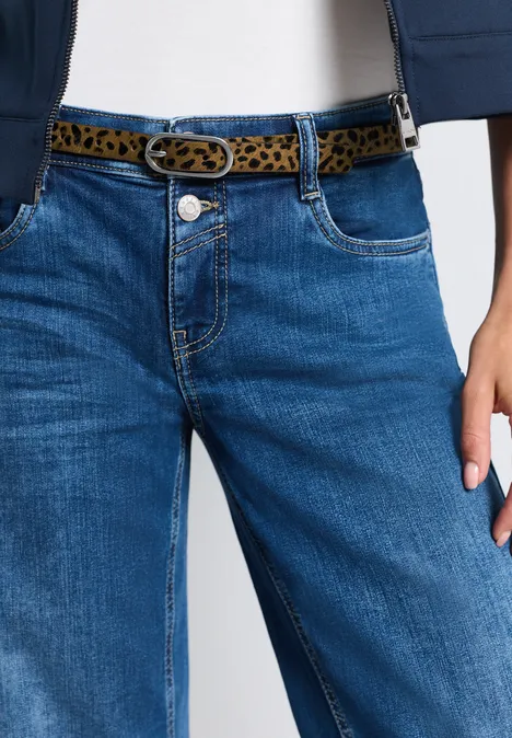 Frau trägt blaue Jeans mit Leopardenmuster-Gürtel und weißem Top
