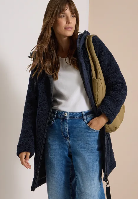 Manteau Teddy à texture contrastée avec capuche dark navy blue Eine Frau trägt eine dunkelblaue Jacke, ein weißes T-Shirt, blaue Jeans und eine olivgrüne Umhängetasche.