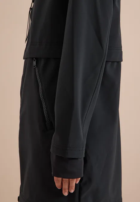 Seitliches Detail einer Person in schwarzer Jacke mit Reißverschlusstaschen und langen Ärmeln.