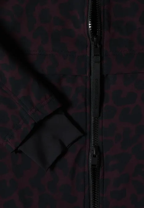 Gros plan d'une veste à motif léopard bordeaux et noir, fermeture éclair visible et couture de poche discrète.