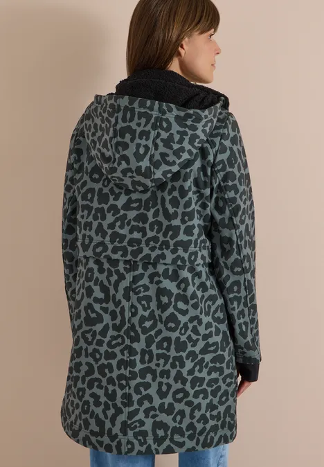 Vue de dos d’une personne portant un manteau mi-long vert foncé à capuche, motif léopard noir.