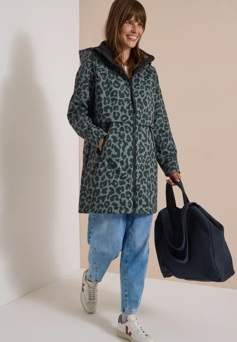Femme en manteau léopard bleu-gris, jean et baskets, portant un grand sac bleu marine.