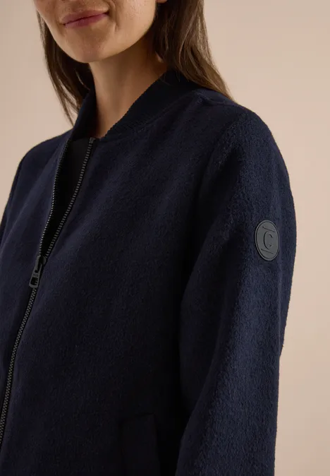 Langer Blouson mit Wollanteil dark navy blue Frau in dunkelblauer Fleece-Jacke mit Reißverschluss und rundem Logo am Ärmel