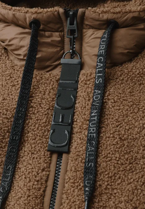 Braune Sherpa-Jacke mit Reißverschluss, schwarzen Kordeln und Schriftband 'ADVENTURE CALLS' an einem D-Ring