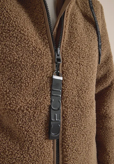 Nahaufnahme eines bräunlichen Teddy-Fleece-Jackenzippers mit Leder-Reißverschlussanhänger